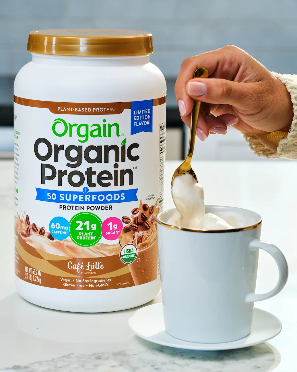 Orgain Café Latte organic protein tub beside a mug and gold spoon