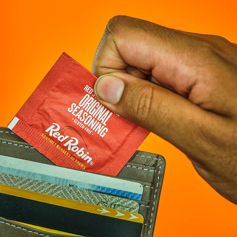 Hand taking a Red Robin seasoning packet from a wallet